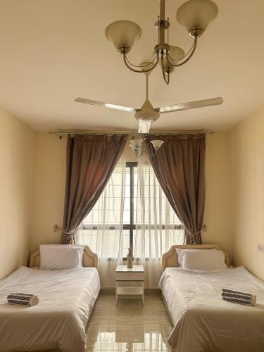 two beds in a room with a window at SIRA apartment 1 in Muscat
