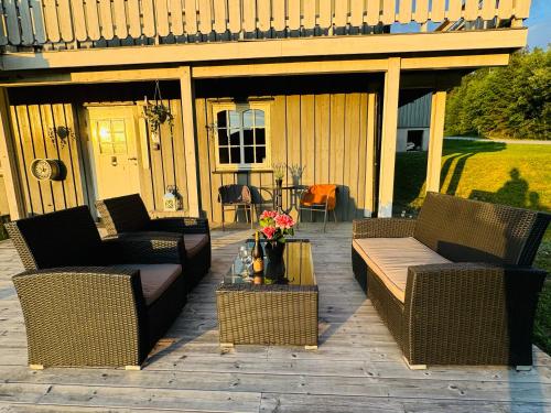 eine Terrasse mit Korbmöbeln auf einer Holzterrasse in der Unterkunft Hjemmekoselig leilighet i underetasje 