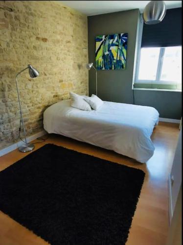 - une chambre avec un lit blanc et un tapis noir dans l'établissement Appartement charmant et élégant de centre ville, à Caen