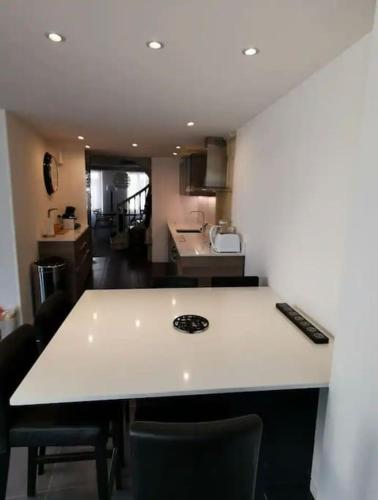 - une cuisine avec un comptoir blanc et des chaises dans l'établissement Appartement charmant et élégant de centre ville, à Caen