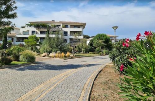une route vide avec des fleurs et un bâtiment dans l'établissement Appart Stella résidence standing, vue panoramique, à Porto-Vecchio
