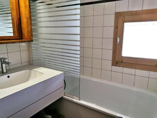 La salle de bains est pourvue d'un lavabo, d'une baignoire et d'une fenêtre. dans l'établissement Résidence Fagot - Le Fagot 15 - Appartement rénové avec goût, proche pistes et commerces MAE-1701, à Valmorel