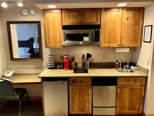 a kitchen with wooden cabinets and a sink and a microwave at MT CB Mountain Side with King Bed, Hot Tub, Pool & Kitchen! in Crested Butte