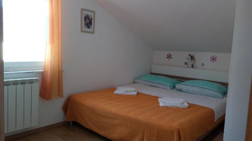 a bedroom with a bed with two pillows and a window at Apartments Vitkovic in Cres