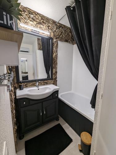 une salle de bain avec un lavabo, une baignoire et un miroir dans l'établissement Appartement bord de mer, piscine et Wifi, à Saint-Cyprien