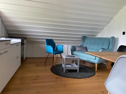 a living room with a table and two blue chairs at Jurabelle in La Côte-aux-Fées