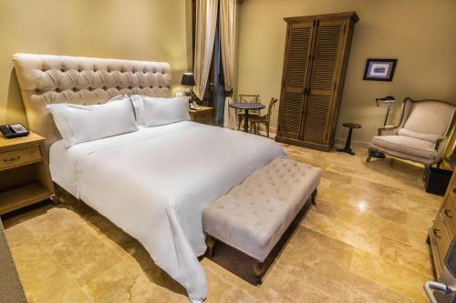 a bedroom with a large white bed and a chair at Bastión Luxury Hotel in Cartagena de Indias