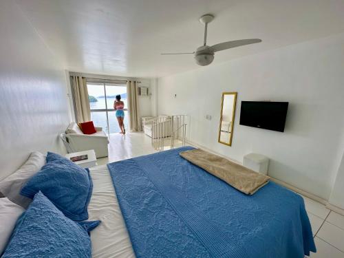 1 dormitorio con 1 cama con sábanas azules y TV en Angra Inn Praia Grande, en Angra dos Reis