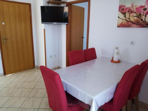 a dining room with a white table and red chairs at Apartments Vitkovic in Cres