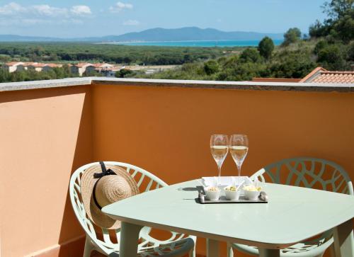 a table with two glasses of wine on a balcony at Nuovissimo Appartamento Vento d'estate in Castiglione della Pescaia