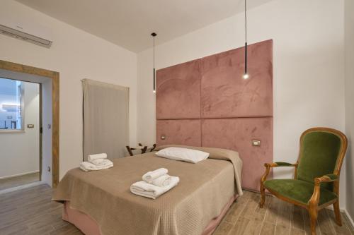 a bedroom with a bed and a green chair at Makó House - in centro città in Andria