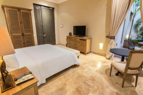 a bedroom with a bed and a desk and a television at Bastión Luxury Hotel in Cartagena de Indias