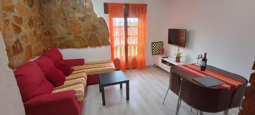 a living room with a red couch and a table at Apartamento Flor de Luna in Santillana del Mar