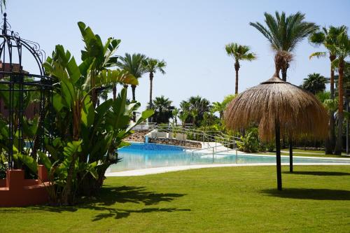 a resort with a swimming pool and palm trees at Playa Granada Apartamentos Moriscos II in Motril