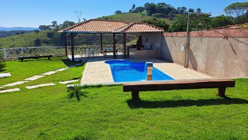 un banco sentado en el césped junto a una piscina en Rancho do Carlinhos, en Ipoema