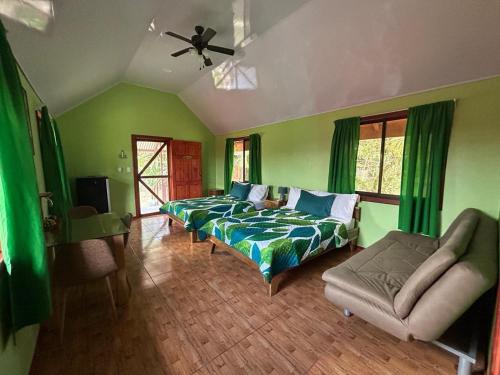 um quarto verde com uma cama e um sofá em Cabinas Tortuguero Sports Fishing em Tortuguero