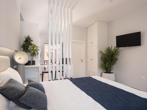 a white bedroom with a bed and a flat screen tv at Elena Seafront Luxury Apartments in Almirida
