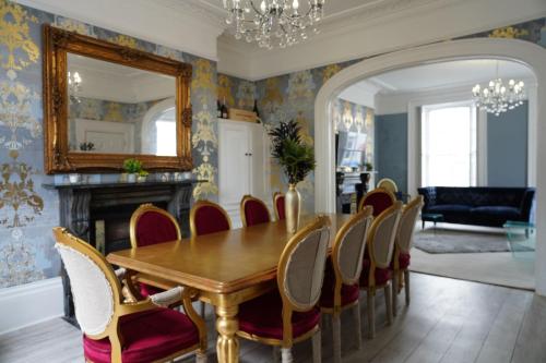 a dining room with a table and chairs and a mirror at THE HOE, BEAUTIFUL 5-BEDROOM HOUSE, GARDEN, SECURE PARKING, SLEEPs 12 in Plymouth