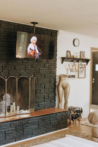 a living room with a tv on a brick fireplace at Dolly House in Sevierville