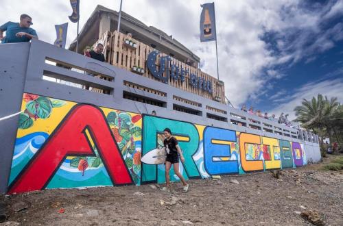 a woman holding a surfboard in front of a cruise ship at New! Mini Casa de Playa in Arecibo