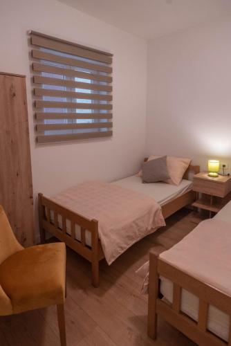 two beds in a room with a window and a chair at Apartman Iko Cista Provo in Cista Provo