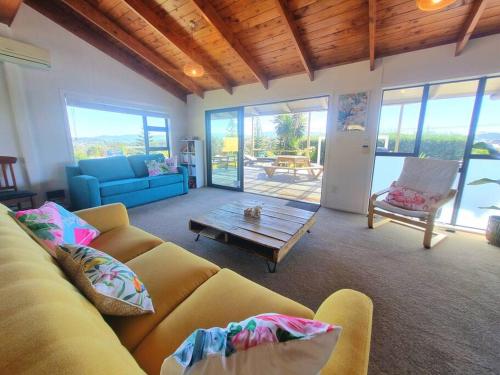 a living room with a couch and a table at Tropical Oasis in Golden Circle in Mangawhai