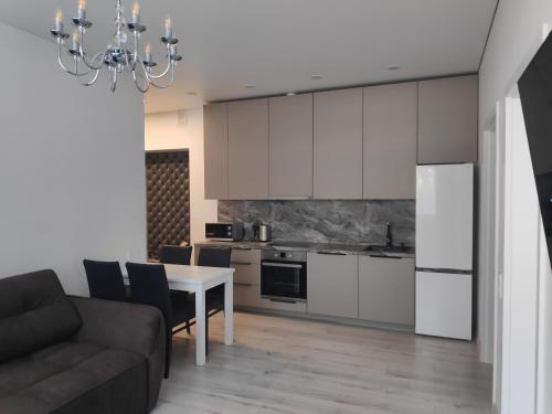 a living room with a table and a kitchen at Aušros Alėjos Apartamentai in Šiauliai