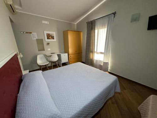 Schlafzimmer mit einem Bett, einem Schreibtisch und einem Fenster in der Unterkunft Borgo Manfria in Gela