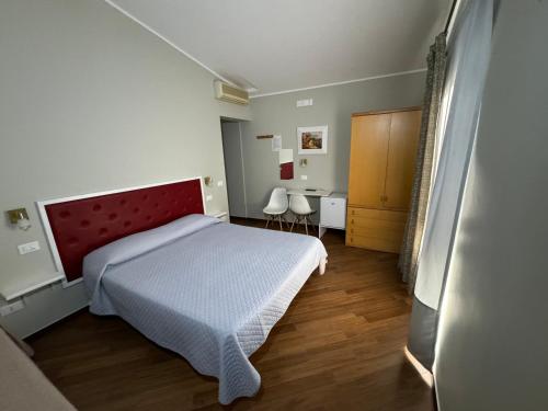 Schlafzimmer mit einem Bett mit rotem Kopfteil und einem Schreibtisch in der Unterkunft Borgo Manfria in Gela