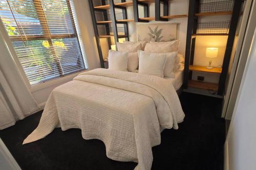 a bedroom with a bed with a white blanket and a window at Apartment 1 - Haddin Court - Executive One Bedroom in Blenheim