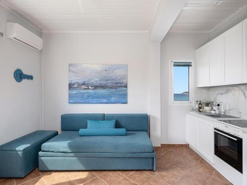 a living room with a blue couch in a kitchen at Elena Seafront Luxury Apartments in Almirida