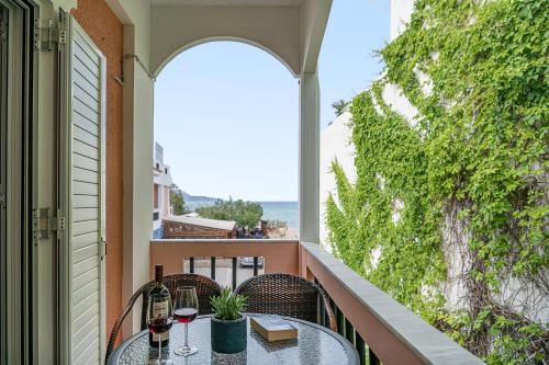 a balcony with a table and two glasses of wine at Elena Seafront Luxury Apartments in Almirida