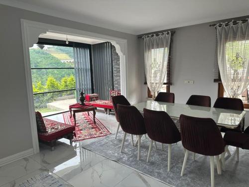 a dining room with a table and chairs and a large window at Zeytinlik Nature House in Akcaabat