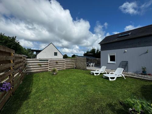 a backyard with two white chairs and a fence at Maison Pors Haor in Crozon