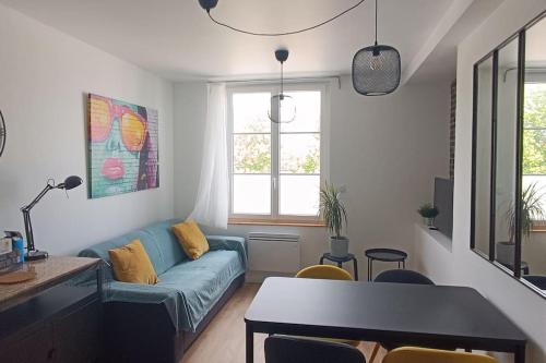 un salon avec un canapé bleu et une table dans l'établissement Actarus-SILS - T1 28 M2, à Caen