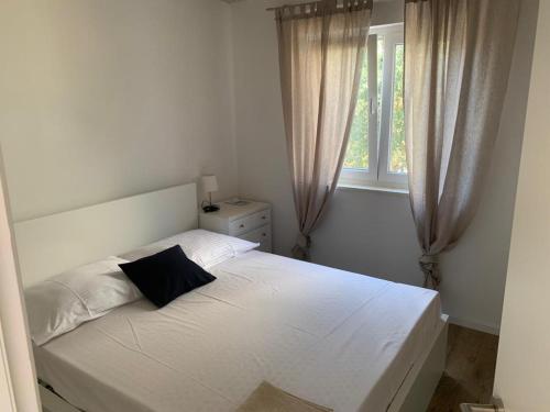 a bedroom with a white bed with a black pillow at TwENty2-Punat Apartments in Punat