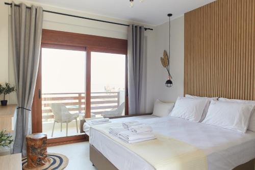 a bedroom with a large white bed with a balcony at seaandolive in Ammouliani