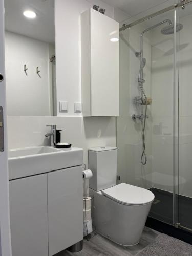 a white bathroom with a toilet and a shower at Apartamento Brisa do Mar in Sesimbra