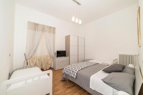 a white bedroom with two beds and a television at Sweet dreams in Montefiascone