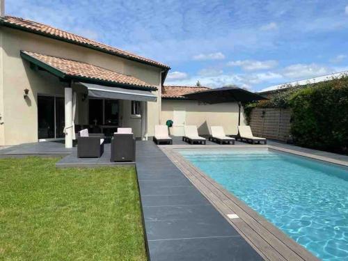 une piscine avec des chaises longues et une maison dans l'établissement Villa familiale 8 personnes, piscine chauffée à 10 kms de la mer, à Saubion