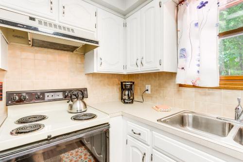 a kitchen with white cabinets and a stove and a sink at Hot Tub and Fire Pit Holiday Island Getaway! in Golden