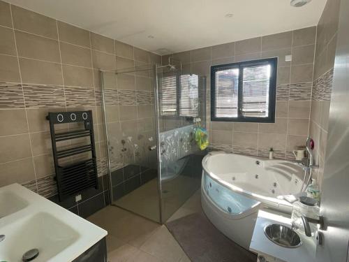 une salle de bain avec une baignoire, une douche et un lavabo dans l'établissement Villa moderne avec piscine, à Saint-Aubin-de-Médoc