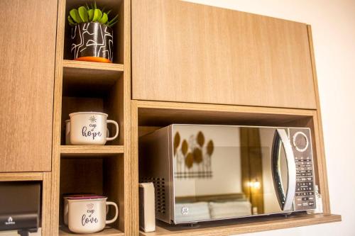 a microwave in a wooden cabinet with two cups at Marina Cerritos Loft Wave Pool and Amenities in Mazatlán