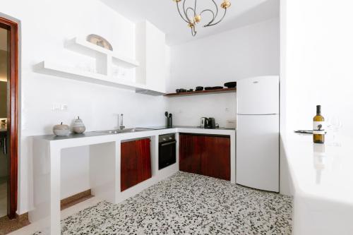 a white kitchen with a sink and a refrigerator at Kaminia Holiday Homes in Éxo Goniá