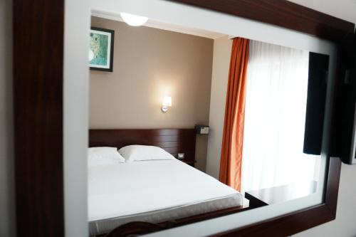 a bedroom with a white bed and a window at Hotel Mediterrane in Sarandë