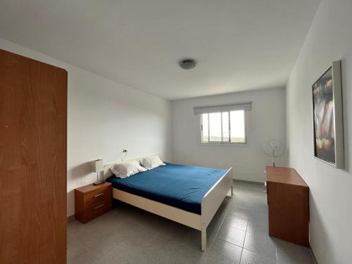 a white bedroom with a blue bed and a window at Finca la Pampa in Arafo