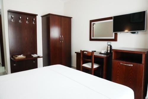 a bedroom with a bed and a desk and a mirror at Hotel Mediterrane in Sarandë
