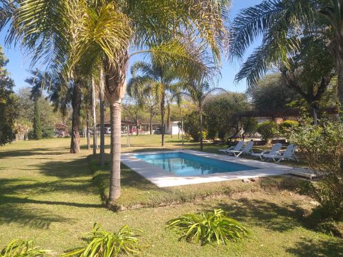 una piscina en un patio con palmeras en Cabañas TERMALES en Termas de Río Hondo