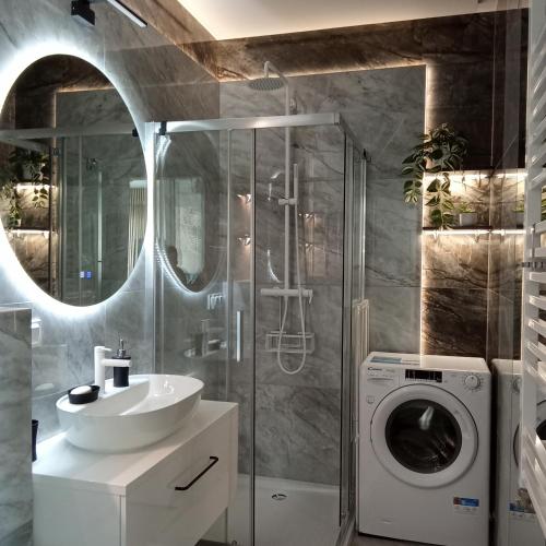a bathroom with a sink and a washing machine at Apartament Aquapark Gold 8 in Reda
