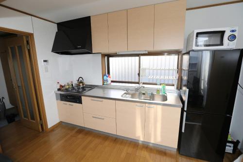 uma cozinha com um frigorífico preto e um lavatório em J's Backpackers em Tóquio